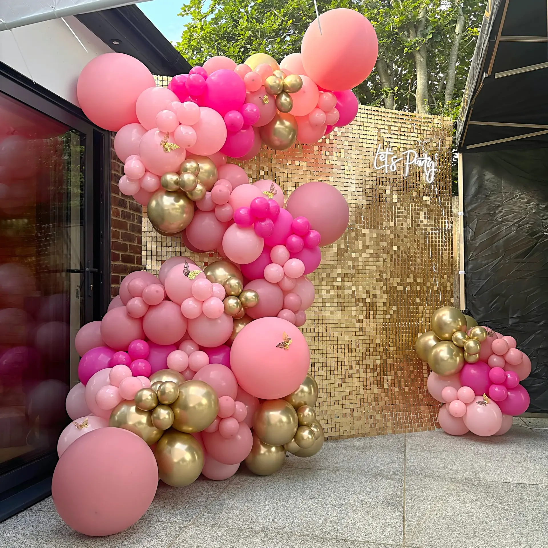Pink and gold balloon installation with a shimmering party backdrop
